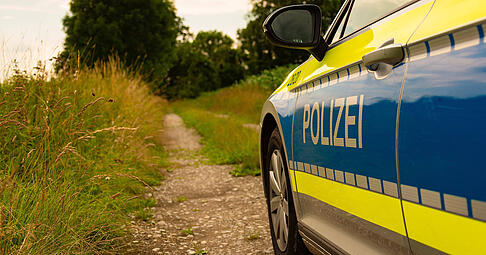 Ein Einsatzfahrzeug, Streifenwagen, der Polizei mit Schriftzug, steht auf einem Feldweg. (Symbolbild)