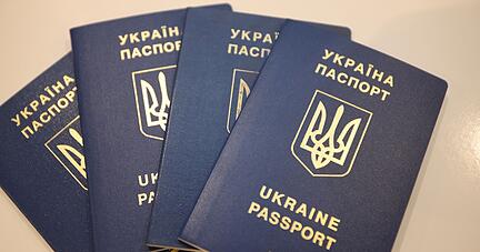 Vier Reisepässe von Geflüchteten aus der Ukraine liegen auf einem Tisch.