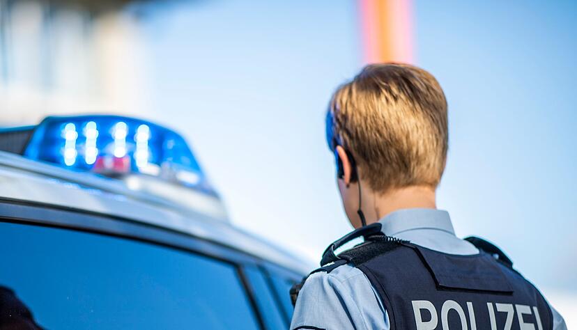 Eine Polizistin steht vor einem Streifenwagen.