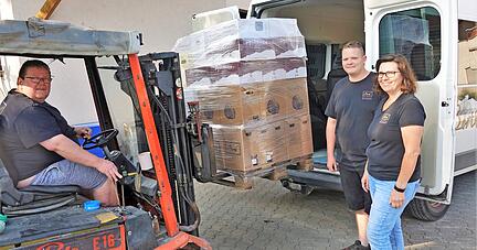 Michael, Nico und Andrea Borth (von links) beladen in Adolzfurt ihren Transporter mit 1080 Flaschen Wein, mit deren Erlös die Winzer-Kollegen an der Ahr unterstützt werden sollen. Foto: Juergen Koch