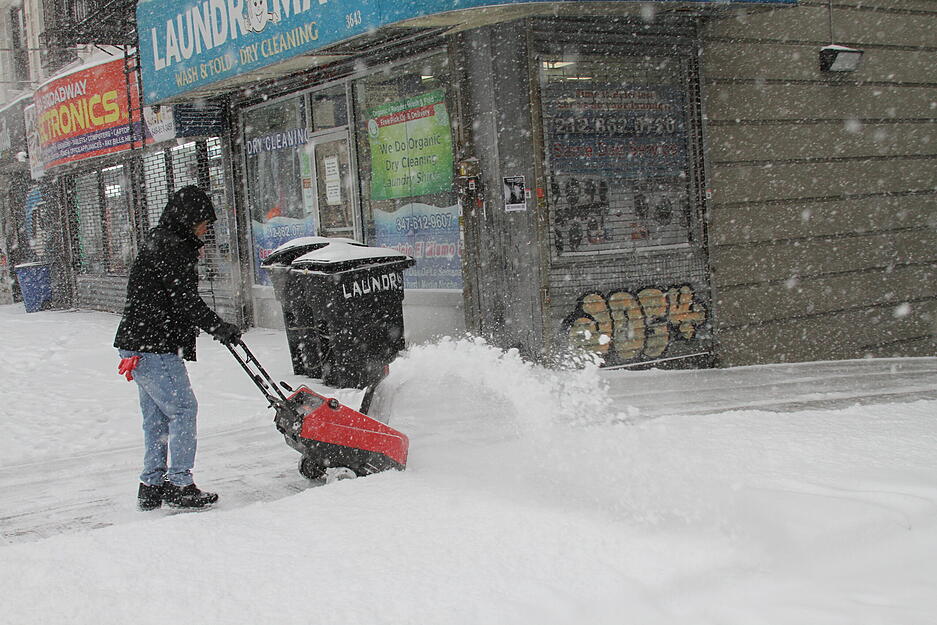 Ein Mann räumt den Gehweg vor einem Haus in New York. Ein Mann räumt den Gehweg vor einem Haus in New York.