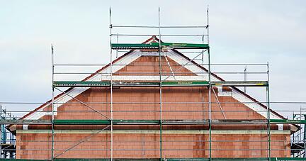 Ein Bauger&uuml;st steht in einem Neubaugebiet an einem Rohbau.