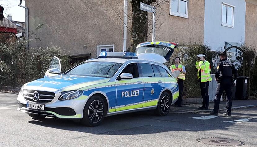 Einsatzkräfte der Polizei stehen an Einsatzfahrzeugen.