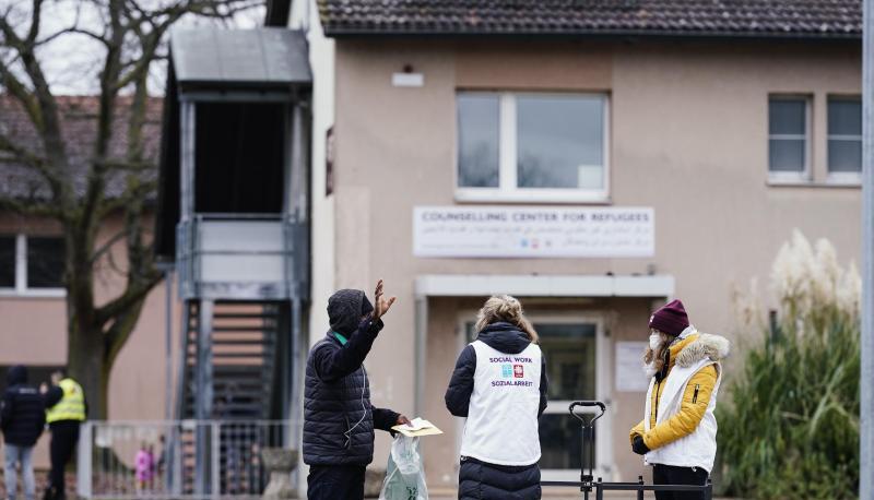 Sozialarbeiterinnen sprechen im Ankunftszentrum für Flüchtlinge mit einem Bewohner.