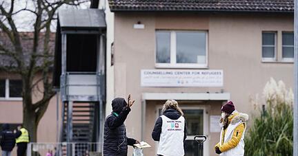 Sozialarbeiterinnen sprechen im Ankunftszentrum für Flüchtlinge mit einem Bewohner.
