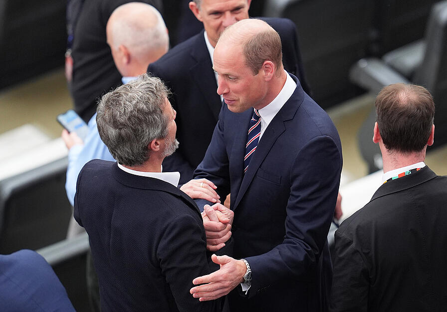 Dänemarks König Frederik X. (l) und William, Prinz von Wales, begrüßen sich vor Spielbeginn auf der Tribüne.