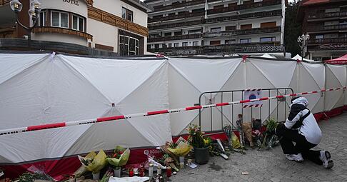 Menschen bringen Blumen in der Nähe der abgeriegelten Bar Le Constellation, wo ein verheerender Brand während der Silvesterfeierlichkeiten Tote und Verletzte forderte. Menschen bringen Blumen in der Nähe der abgeriegelten Bar Le Constellation, wo ein verheerender Brand während der Silvesterfeierlichkeiten Tote und Verletzte forderte.