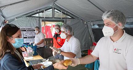 Helfer vom Roten Kreuz geben in Ahrweiler Essen aus. Dreimal täglich werden mehr als 10000 Mahlzeiten für die Opfer der Flutkatastrophe und die zahlreichen Helfer zubereitet.