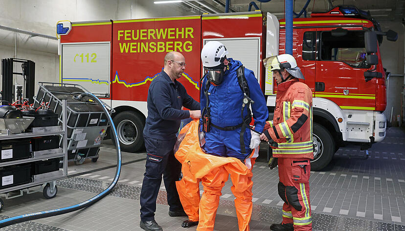 Für die "Einkleidung" mit dem Schutzanzug braucht es Hilfestellung durch Thorsten Maier (links) und Nils Marian. Christian Herzog hat bereits einen feuerfesten Overall an und das Atemschutzgerät aufgesetzt.