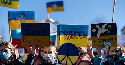 Demonstranten halten Schilder mit den Farben der ukrainischen Flagge in die Luft. Die Organisation Fridays for Future geht an diesem Donnerstag weltweit auf die Straße, um ihre Solidarität mit der Ukraine zu bekunden und um gegen den Angriff Russlands auf das Land zu protestieren.