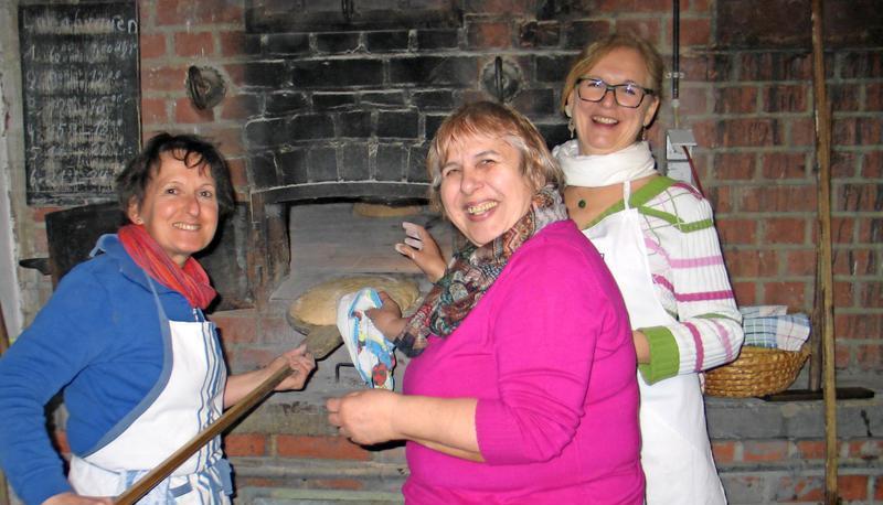 Susanne Weingart-Fink schiebt gemeinsam mit Brigitte Barthau und Ingrid Vogt (von links) die Brote in den Backofen.