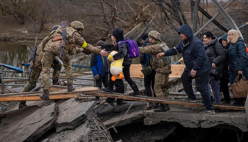 Ukrainische Soldaten helfen einer fliehenden Familie bei der Überquerung des Flusses Irpin in den Außenbezirken von Kiew. Ukrainische Soldaten helfen einer fliehenden Familie bei der Überquerung des Flusses Irpin in den Außenbezirken von Kiew.