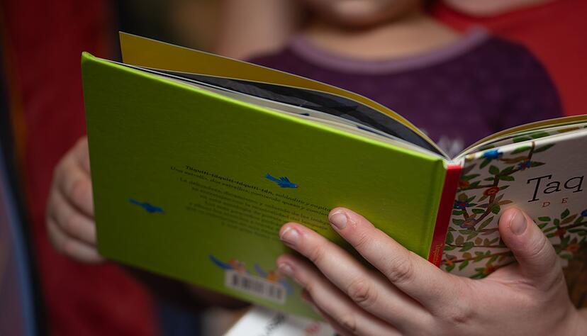 ILLUSTRATION. Eine Mutter liest ihrer kleinen Tochter im Kinderzimmer aus einem Buch vor.