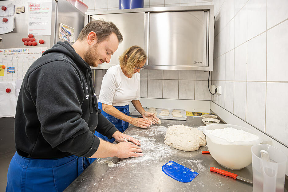 Teilnehmer lernen im Kurs, warum gutes Brot kräftig geknetet werden muss.