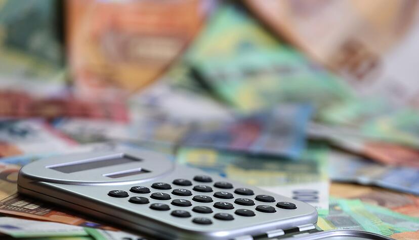 Ein Taschenrechner liegt auf verschiedenen Euro-Banknoten. (Symbolbild)