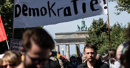 "Demokratie!" steht auf einem Banner, das von Teilnehmern auf der Demonstration gegen die Corona-Beschr&auml;nkungen vor dem Brandenburger Tor Anfang August getragen wird.