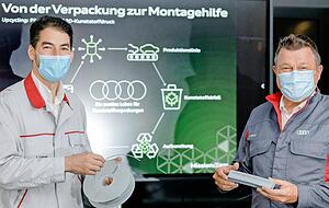 Jérémy Lecoq (links) und Volker Eitrich halten das Ergebnis eines im Werk entwickelten Upcyclings hoch. Aus unvermeidbarem Verpackungsmaterial entsteht Filament, Kunststoff in Drahtform, mit dem im 3D-Druck Montagehilfen hergestellt werden.
