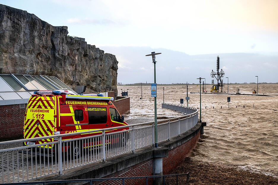 Ein Einsatzfahrzeug der Feuerwehr steht bei Sturmflut am Ufer der Wesermündung in Bremerhaven.