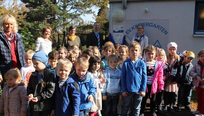 Jetzt ist es offiziell: Pfarrer Friedhelm Bokelmann und Rathausmitarbeiterin Jessica Wells haben das Schild enth&uuml;llt, das den Kindergarten als Sprach-Kita ausweist.
Foto: Tanja Ochs