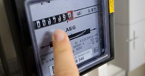 Eine Person liest den Stromverbrauch an einem Wechselstromzähler ab. (Symbolbild)