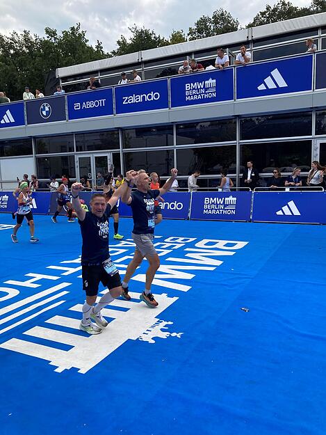 Timo Bauer (vorn) und Jan Häfele laufen beim Berlin-Marathon gemeinsam über die Ziellinie (Arme oben).