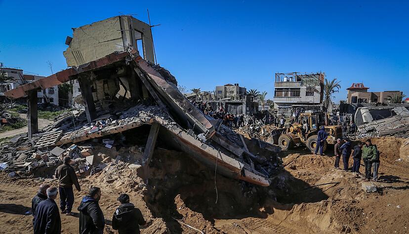 Pal&auml;stinenser beobachten, wie Mitarbeiter des Zivilschutzes Leichen aus den Tr&uuml;mmern eines durch einen israelischen Luftangriff zerst&ouml;rten Hauses bergen.