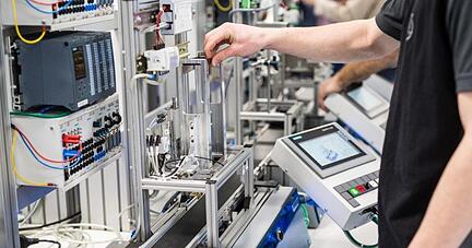 Auszubildende arbeiten im Daimler-Ausbildungszentrum in einem Industrie-4.0-Labor an einem Modell, das eine moderne Automobilproduktionsstra&szlig;e nachempfindet.