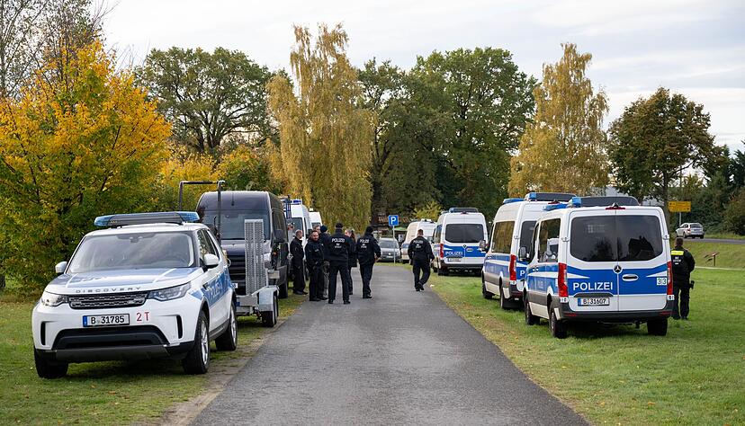 Polizeiautos stehen auf einer Wiese in Tauche.