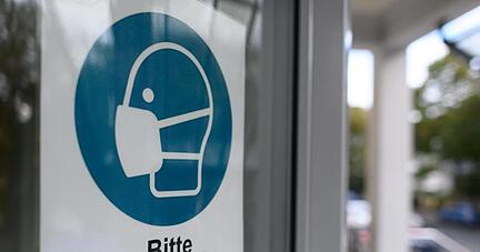 Ein Schild "Bitte Mundschutz tragen" ist zu sehen.