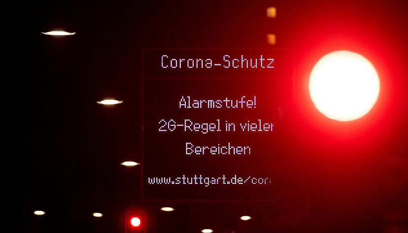 Eine Anzeige weist in der Stuttgarter Innenstadt auf die Corona-Alarmstufe "2G-Regel in vielen Bereichen!" hin, w&auml;hrend eine Ampel ein rotes Signal zeigt. Seit 17. November gilt in Baden-W&uuml;rttemberg die Corona-Alarmstufe, bei der Ungeimpfte von der Teilnahme an vielen Freizeit-, Kultur- und Sportveranstaltungen weitgehend ausgeschlossen sind. Foto: dpa
