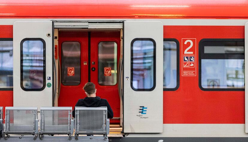 Ein Mann sitzt an einem Bahnhof vor einem Regionalzug auf der Bank. Ein Mann sitzt an einem Bahnhof vor einem Regionalzug auf der Bank.