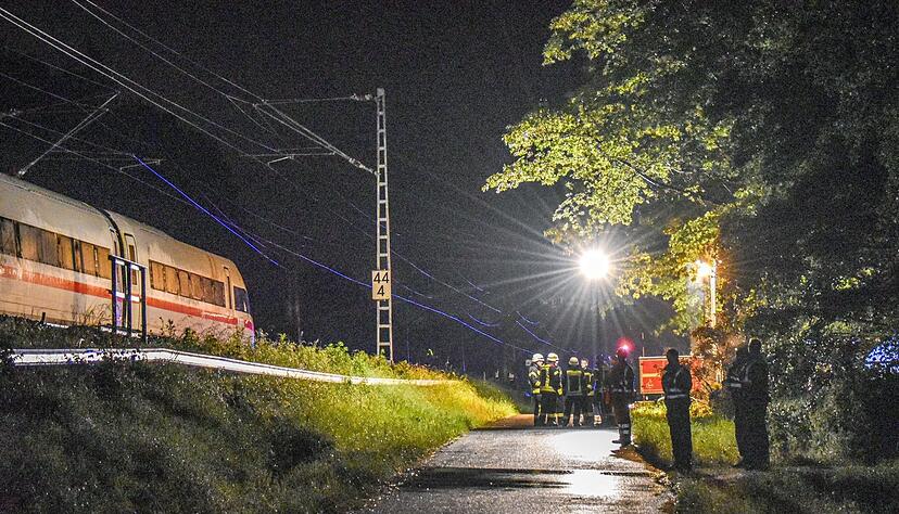 Einsatzkräfte stehen am Abend an der Bahnlinie bei Schwäbisch Gmünd.