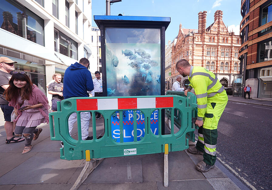 Ein neues Kunstwerk von Banksy mit schwimmenden Fischen, das auf einem Polizeikasten in der Londoner Innenstadt erschienen ist, wird von Arbeitern abgesperrt. Es ist bereits das siebte Werk zum Thema Tiere, das der schwer fassbare Stra&szlig;enk&uuml;nstler diese Woche auf Instagram gepostet hat.