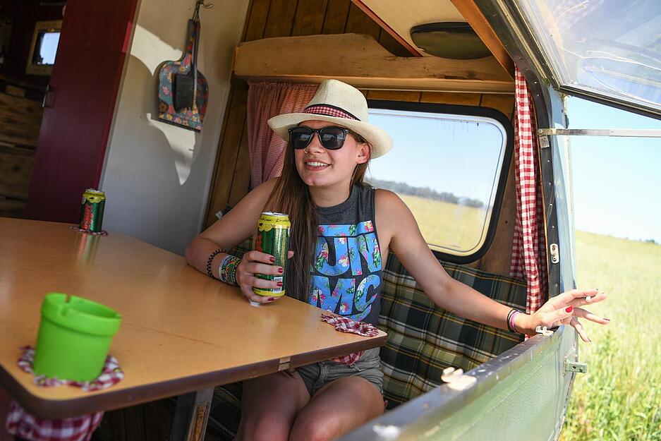 Eine Festivalbesucherin aus Neuravensburg sitzt am ge&ouml;ffneten Heckfenster eines Campingwohnwagens, der in einer kilometerlangen Warteschlange steht.