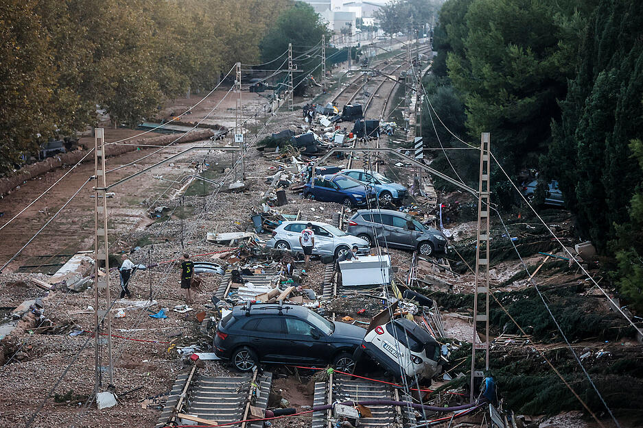 Autos, die durch das heftige Unwetter weggeschwemmt wurden, stehen auf den Gleisen. Dutzende Menschen gelten weiterhin als vermisst, fast 100 sind tot.
