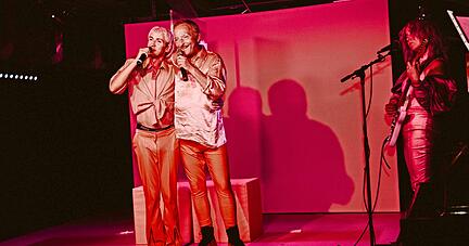 Genderfluide Liebe in rosaroten Zeiten: Jakob Spiegler (links) und Andreas Posthoff im "Heilbronner Leibgericht" auf dem Theaterschiff, rechts Musikerin Vanessa Binder.  
Foto: Nico Kuhn