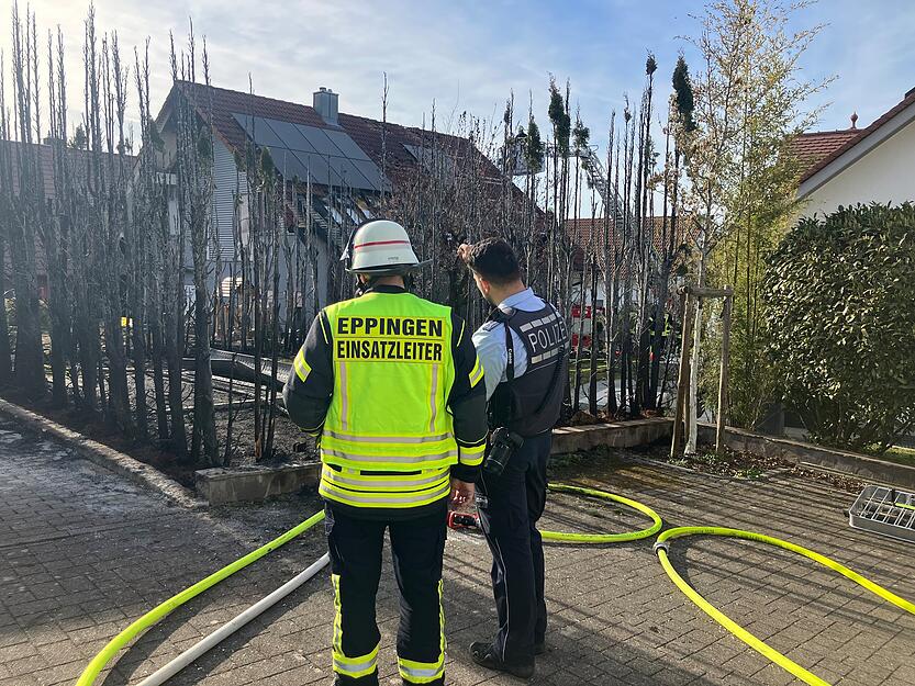 Die Feuerwehr ist mit einer Drehleiter im Einsatz und deckt eine Solaranlage auf einem Hausdach ab.