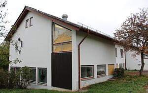 Mehrere zerschlagene Scheiben sind mit OSB-Platten notd&uuml;rftig geflickt.