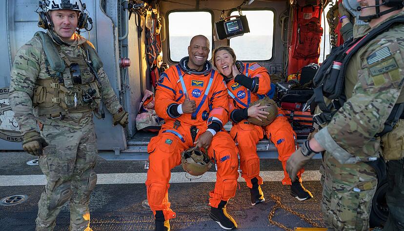 Auf diesem von der NASA zur Verf&uuml;gung gestellten Foto sitzen die Astronauten Victor Glover, Artemis-II-Pilot (l) und Christina Koch, Artemis-II-Missionsspezialistin, auf einem MH-60 Seahawk der Navy auf dem Flugdeck der USS John P. Murtha, nachdem sie und ihre Kameraden im Pazifischen Ozean vor der K&uuml;ste Kaliforniens nach der Wasserlandung aus ihrem Orion-Raumschiff geholt wurden.