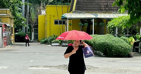 Viele sch&uuml;tzen sich mit Schirmen vor der Sonne.