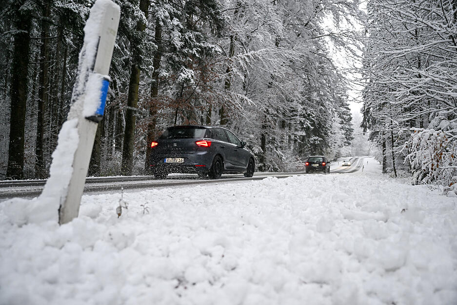 Autos fahren über eine Straße durch den verschneiten Wald. Über Nacht hat es in Oberschwaben und dem Allgäu zu schneien begonnen.