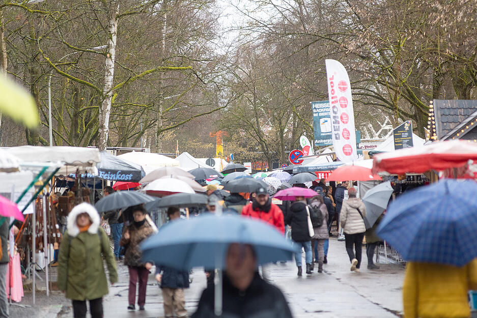 Mit Regenschirmen oder Kapuzen wagen sich einige Besucher &uuml;ber den Heilbronner Pferdemarkt am Samstag.