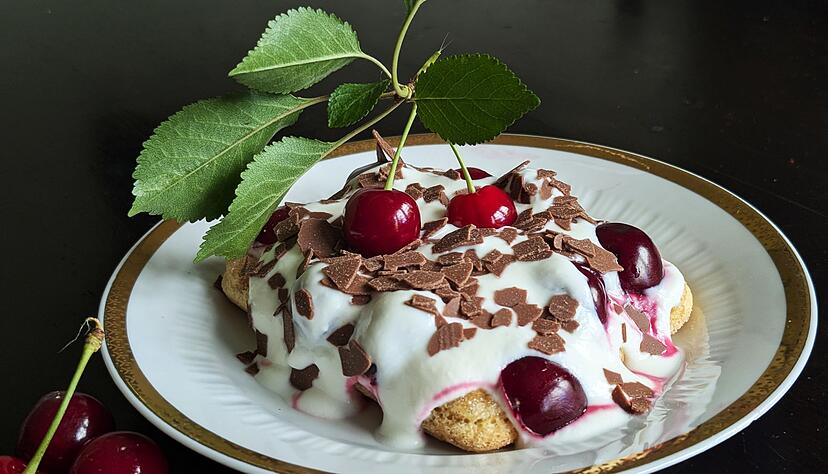 Auf die mit Espresso getr&auml;nkten L&ouml;ffelbiskuits kommen eine Quark-Sahne-Masse und reichlich Kirschen. Das Tiramisu wird mit Schokoraspeln getoppt.