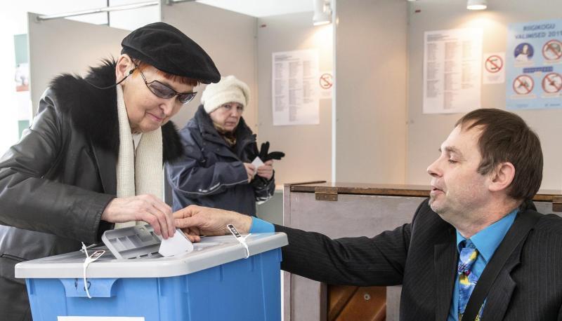 Ein Mitarbeiter der Wahlkommission hilft in einem Wahllokal in Tallinn einer Frau bei der Stimmabgabe.