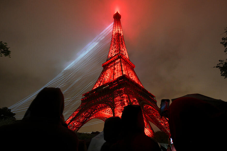 Lichter beleuchten den Eiffelturm in Paris während der Eröffnungsfeier der Olympischen Spiele 2024.