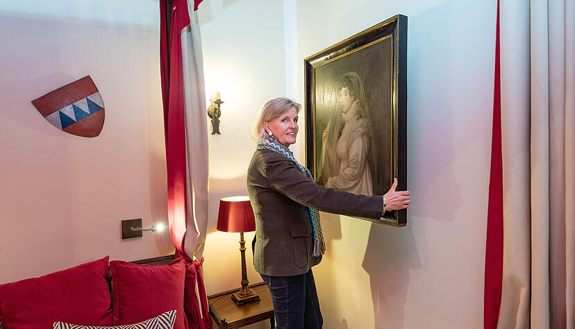 Birgit Baronin von Berlichingen richtet das Bild einer in Weiß gekleideten Frau neu aus. Seltsamerweise hängt das Gemälde manchmal schief an der Wand.