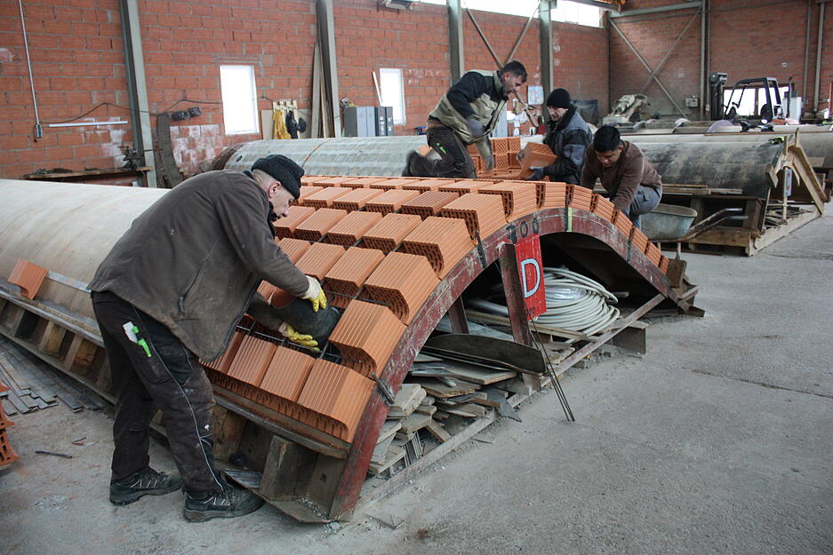 In der Montagehalle werden Ziegel zu einem Fertiggew&ouml;lbe aufgereiht.