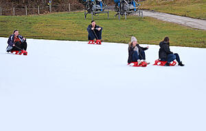 Rodler fahren auf einer Piste in Garmisch-Partenkirchen an Schneekanonen vorbei. Rodler fahren auf einer Piste in Garmisch-Partenkirchen an Schneekanonen vorbei.