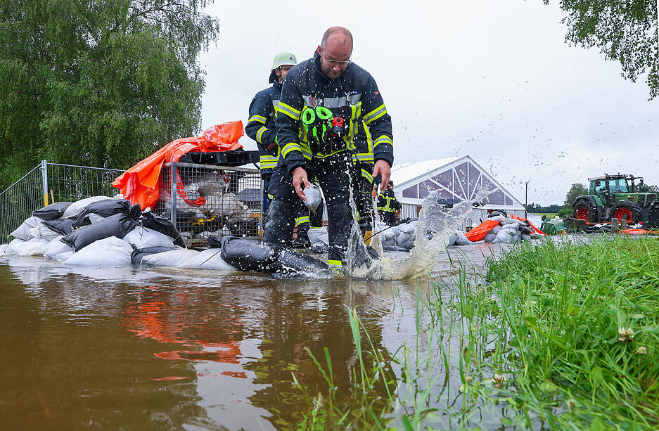 Einsatzkräfte der Feuerwehr errichten vor dem Festzelt des Musikverein Moosheim-Tissen einen Damm mit Sandsäcken. Das dortige Sommerfest findet aufgrund von Hochwasser nicht statt. Der Nonnenbach ist über die Ufer getreten.