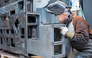 Ein Mitarbeiter pr&uuml;ft Schwei&szlig;n&auml;hte an einer Metallkonstruktion.